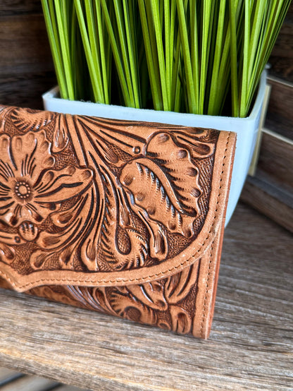 Brown tooled leather wallet flap with floral embossing and stitched edge, close-up.