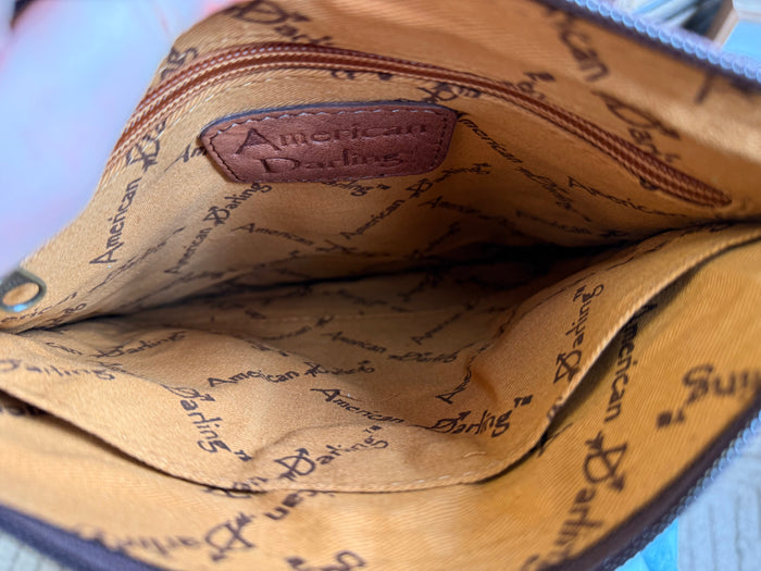 Cowhide crossbody purse interior with beige printed lining and stitched logo patch