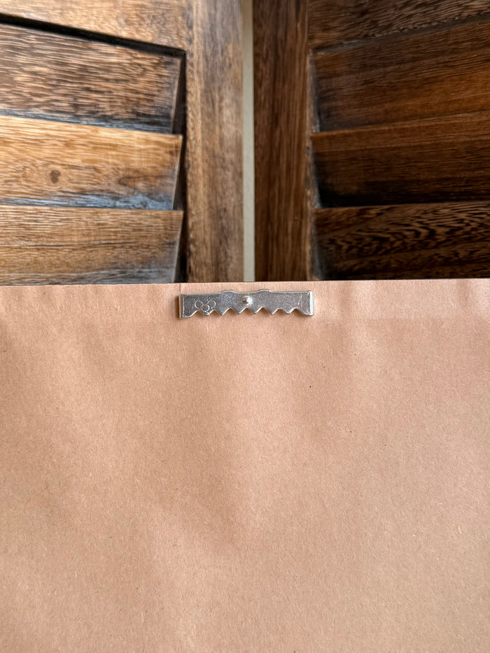 Dark metal frame hanger clip on tan backing for framed wall art