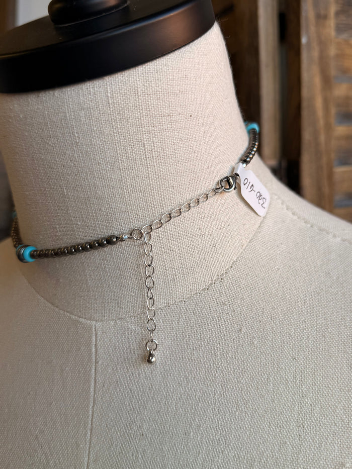 Turquoise and silver bead necklace detail with hanging chain and tag