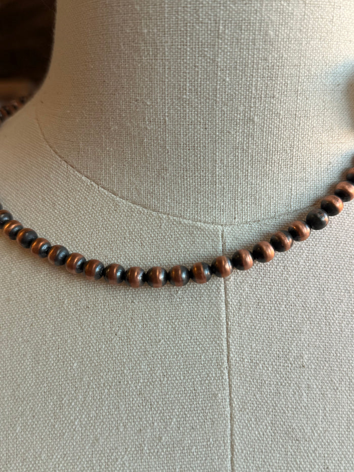 Close-up of a genuine copper bead necklace with small round copper-tone beads