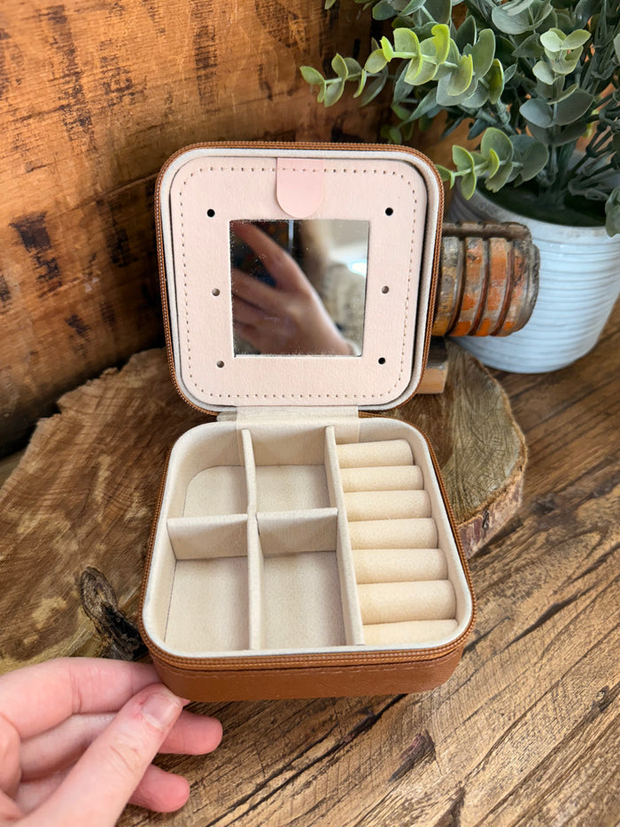 Beige travel jewelry box open with cushioned compartments for rings or small items