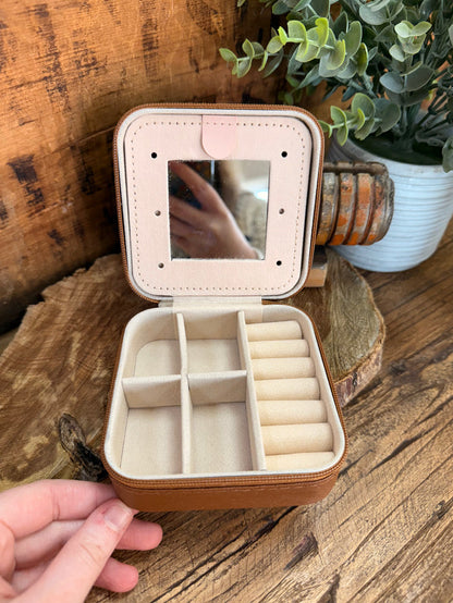 Beige travel jewelry box open with cushioned compartments for rings or small items
