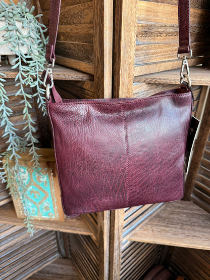 Plum leather crossbody bag with wide main front, top strap, and subtle texture