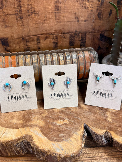 Silver-tone turquoise stud earrings set on cards, featuring horseshoe, cactus, and longhorn