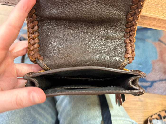 Cowhide crossbody pouch bag interior view with dark lining and braided top edge