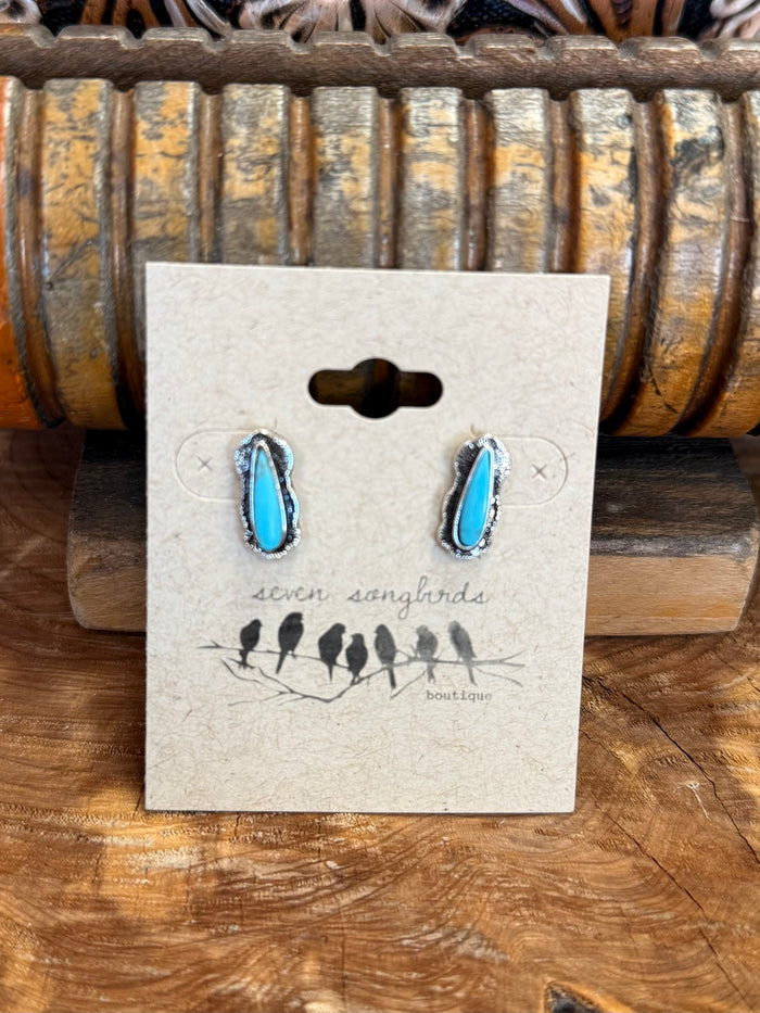Silver teardrop stud earrings with turquoise-blue stones, displayed on jewelry card.
