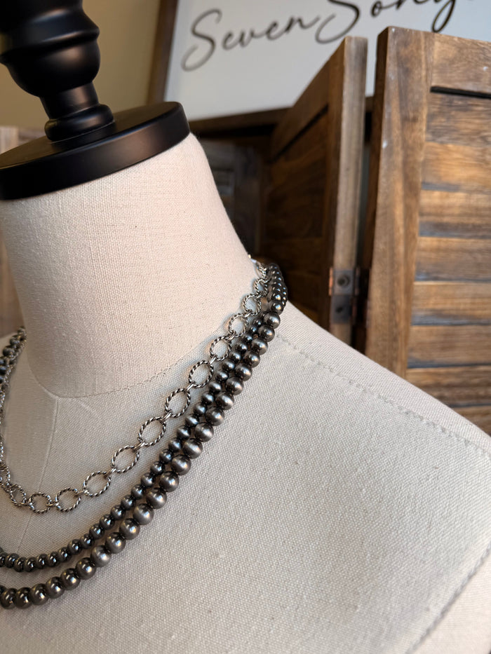 Triple-layer bead and chain necklace, close-up of silver-tone links and dark beads