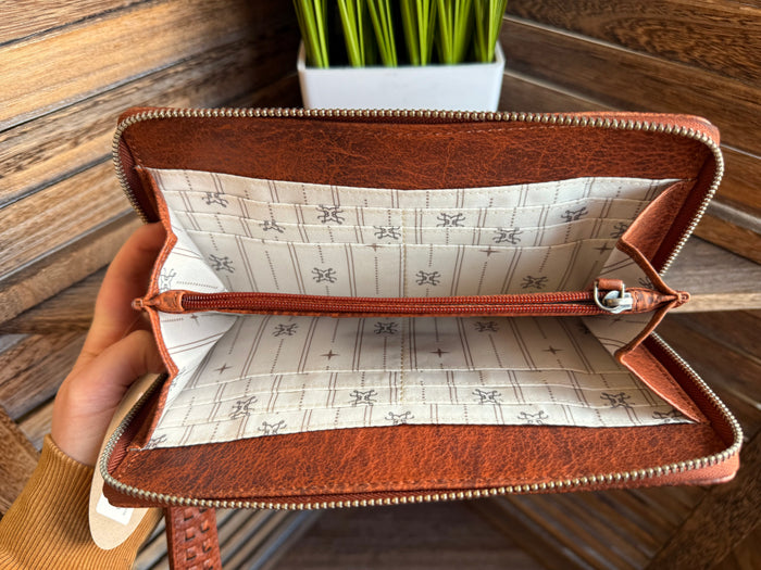 Rusty brown wristlet wallet open inside, tan patterned lining and gold-tone zipper