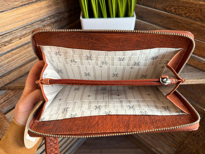 Rusty brown wristlet wallet open inside, tan patterned lining and gold-tone zipper
