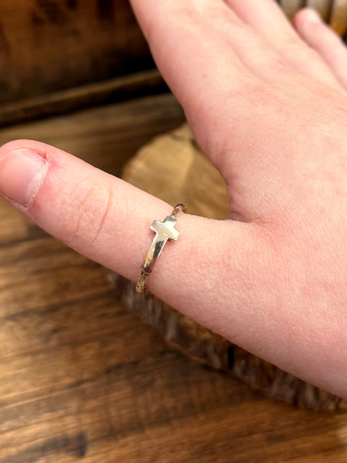 Dainty silver cross ring, close-up on finger