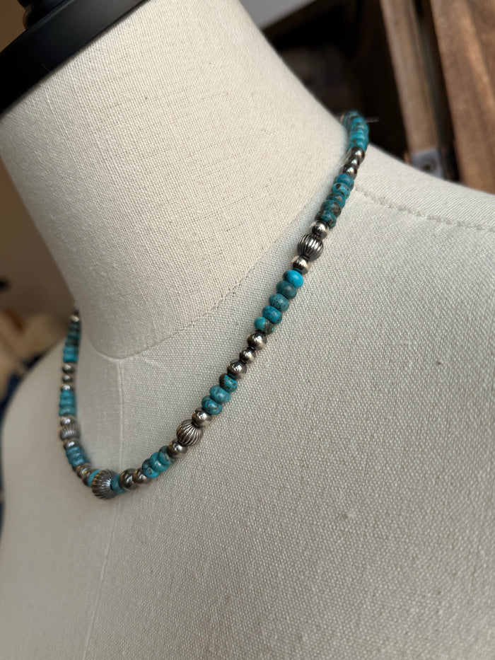 Close-up of graduated turquoise and sterling silver bead necklace with round spacer beads