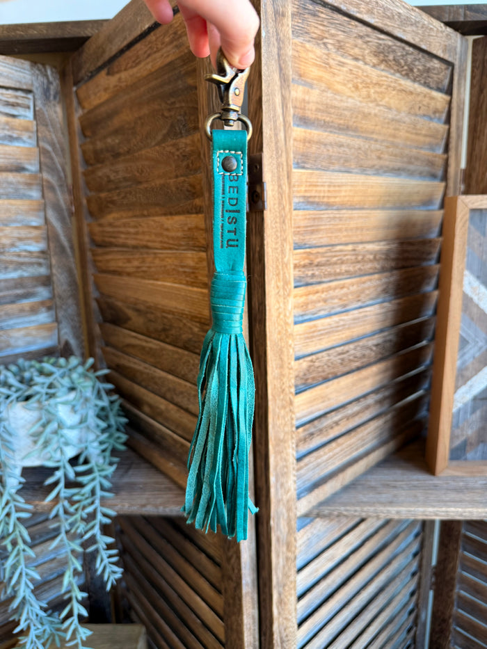 Teal leather tassel clip with metal clasp and hanging fringe on a key ring