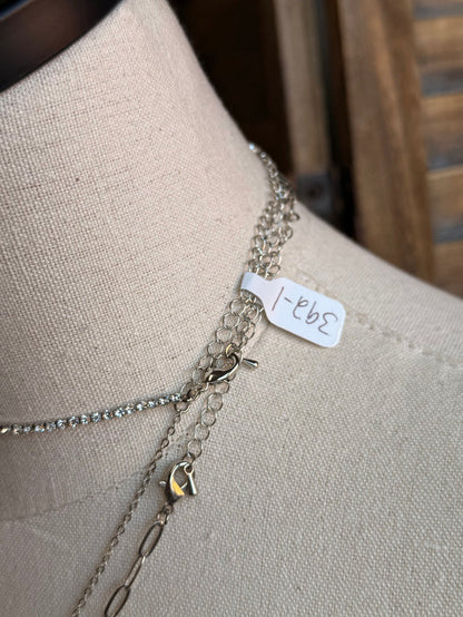 Silver necklace chains with clasp and small tag detail near the neckline