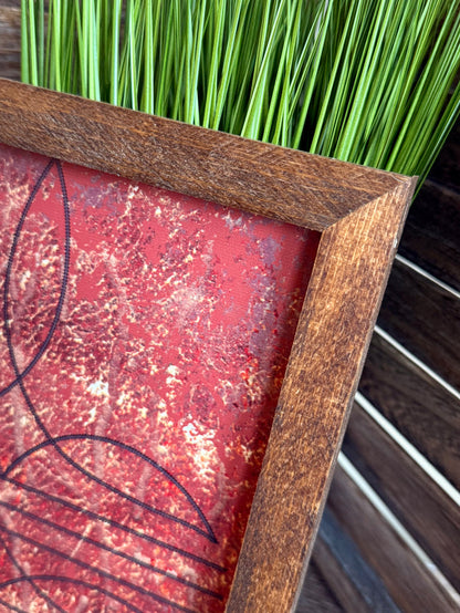 Close-up: rustic wood frame with red speckled panel and curved line artwork