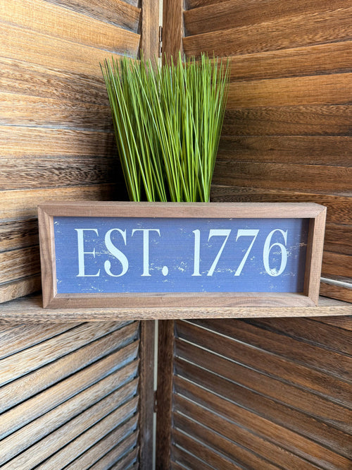 Framed “EST. 1776” wall artwork, blue panel with light wood frame, 12x4