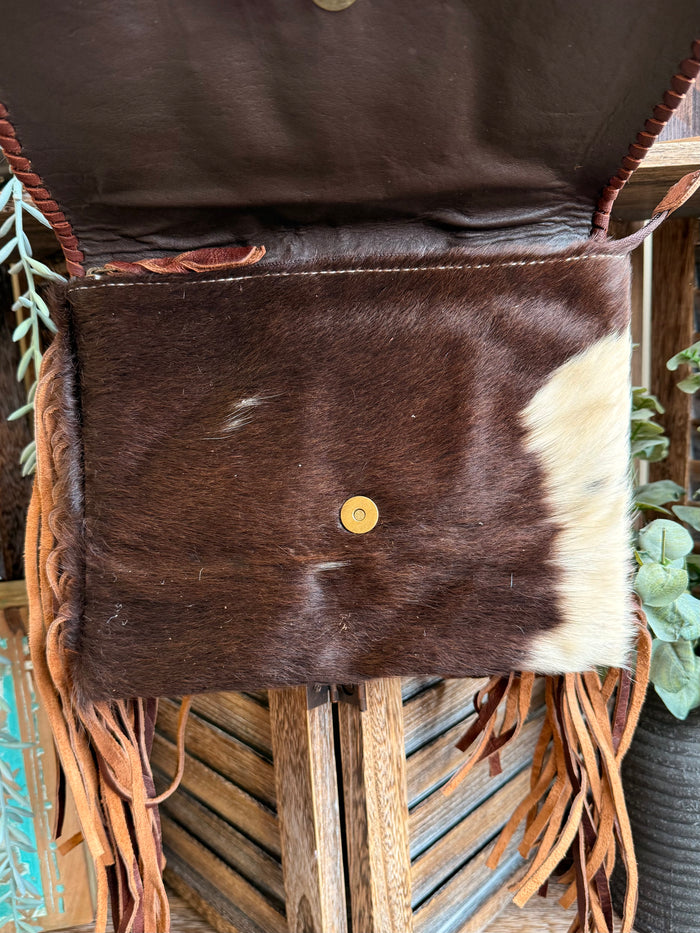 Fringed cowhide crossbody purse with solid front panel and small round gold snap