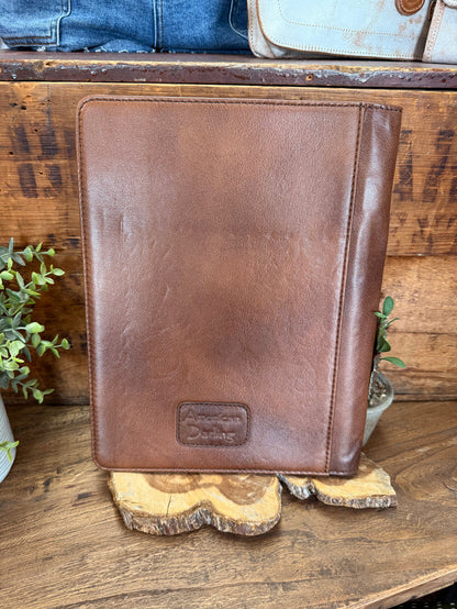 Brown leather folio notebook back panel with minimal embossed logo patch