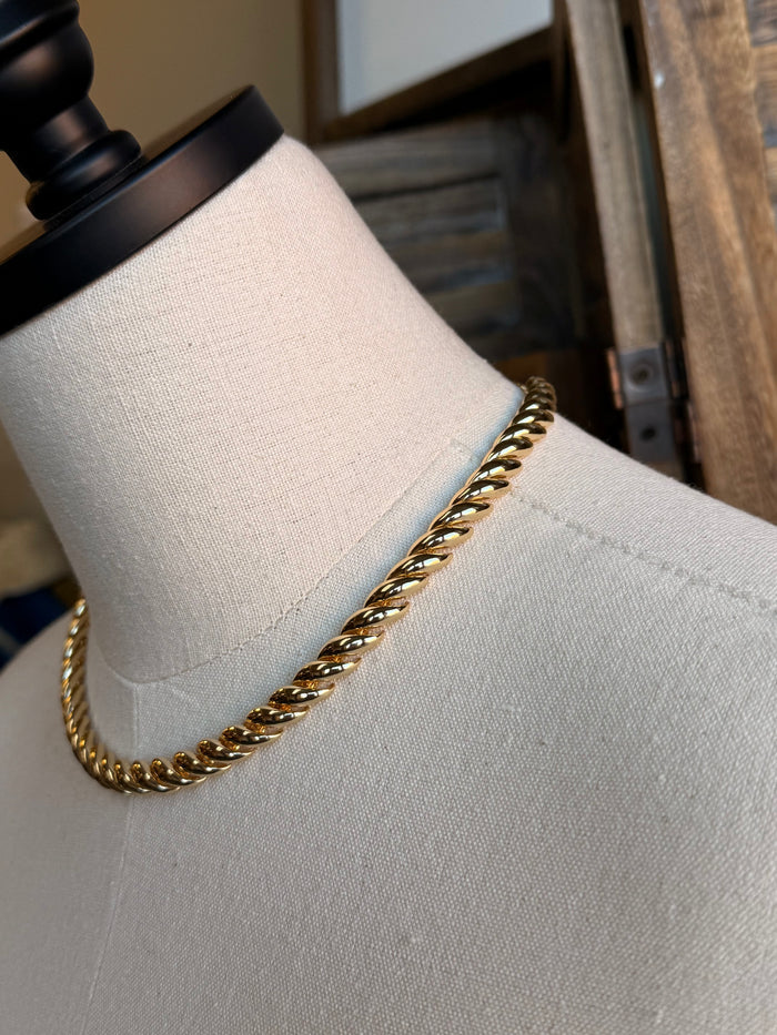 Chunky gold chain necklace close-up on mannequin neck, twisted curb links, shine
