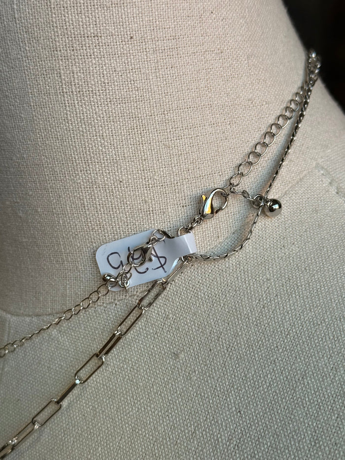 Silver-tone chain necklace detail with cross pendant and clasp hardware