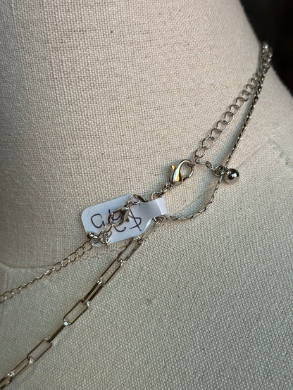 Silver-tone chain necklace detail with cross pendant and clasp hardware