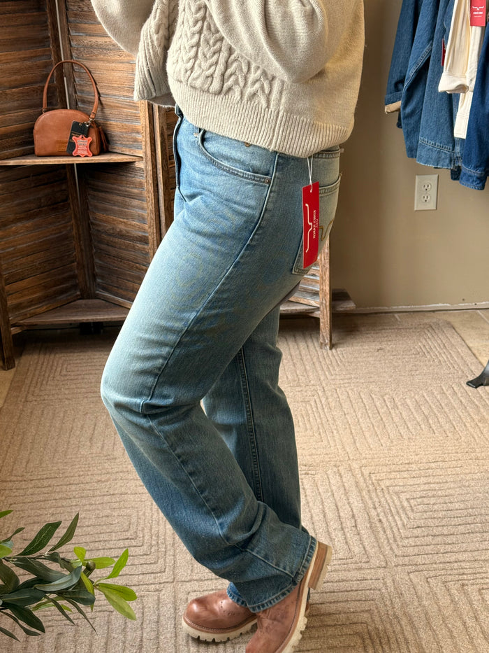 Mid-wash blue jeans with straight-leg hem and contrast stitching; side view.