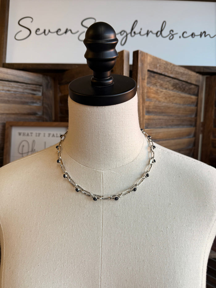 Chunky silver chain necklace with small black stone beads, on a mannequin