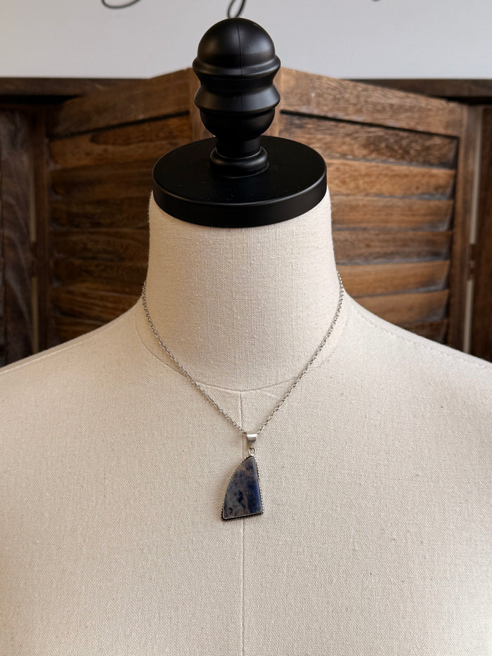 Silver chain necklace with blue triangular stone pendant on mannequin