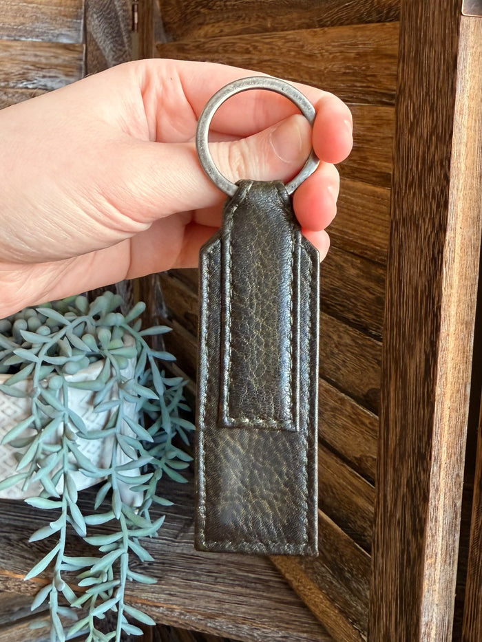 Olive braided leather keychain detail with metal ring and stitched leather panel