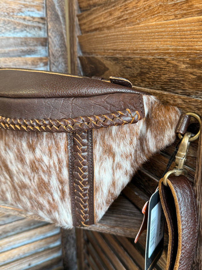 Hair-on cowhide fanny pack side view with braided piping and brass hardware