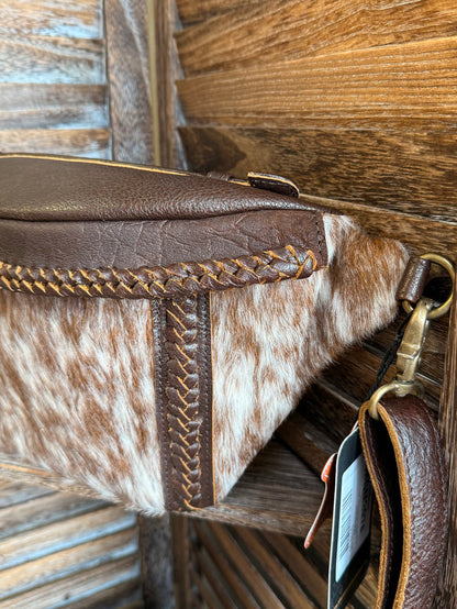 Hair-on cowhide fanny pack side view with braided piping and brass hardware
