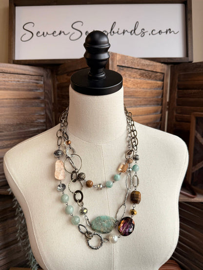 Layered stone bead necklace with blue-green oval, purple faceted beads, pearl-like accents