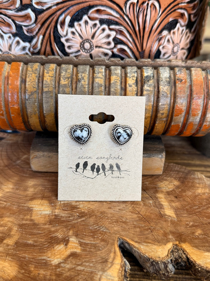 Heart-shaped silver earrings with black-and-white stone centers, on display card