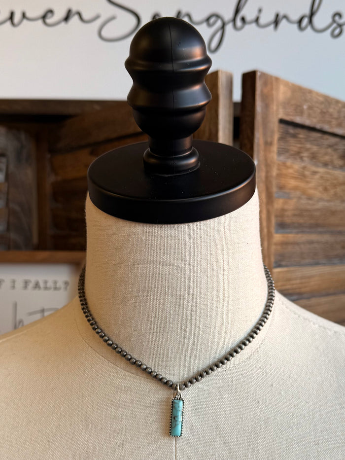 Silver-tone chain necklace with turquoise rectangular pendant, close front view