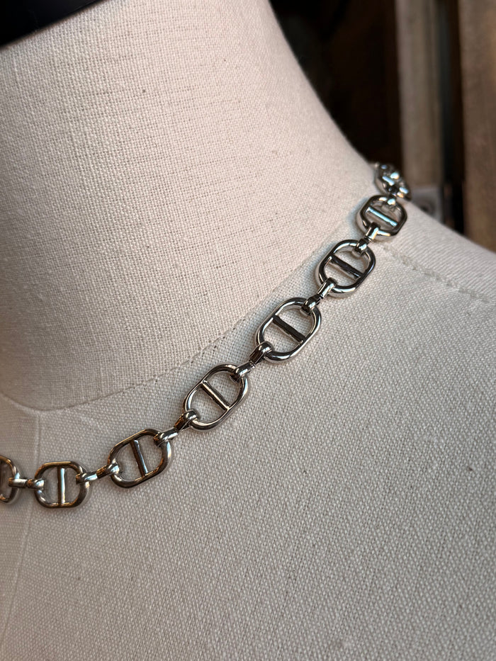 Close-up silver bottle-cap link necklace chain detail