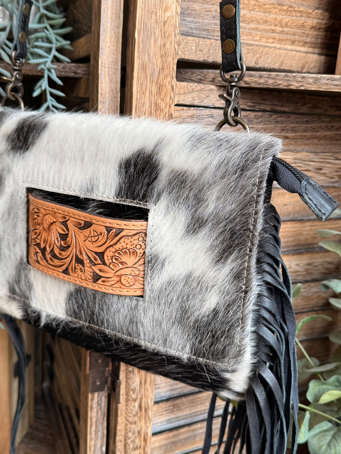 Cowhide crossbody clutch with tan engraved flap, top handle chain, and black fringe