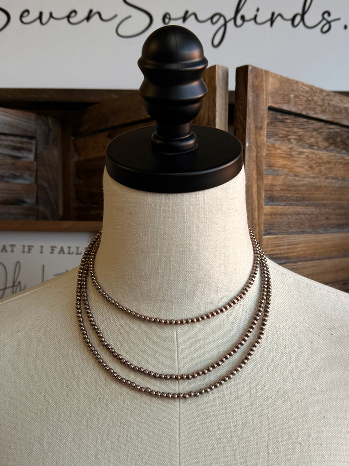 Triple layer stack chain necklace on mannequin, copper-toned links, front view