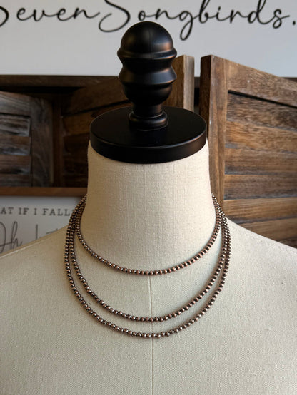 Triple layer stack chain necklace on mannequin, copper-toned links, front view