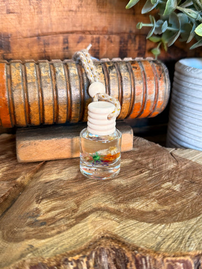 Mini reed diffuser with clear bottle and white stacked reed caps on wooden surface