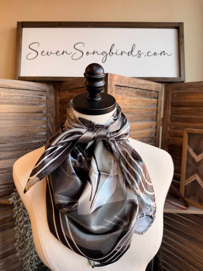Wild rag scarf in gray and black with horse collage print, knotted on mannequin