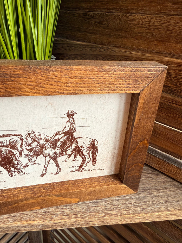 Corner view of wood framed cattle drive print with cowboys and horses in sketch