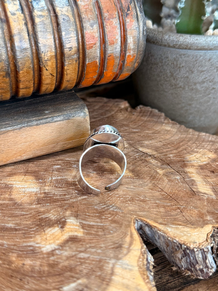 Adjustable silver-plated ring with oval green stone, side view of open band