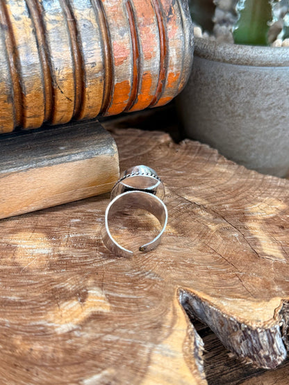 Adjustable silver-plated ring with oval green stone, side view of open band