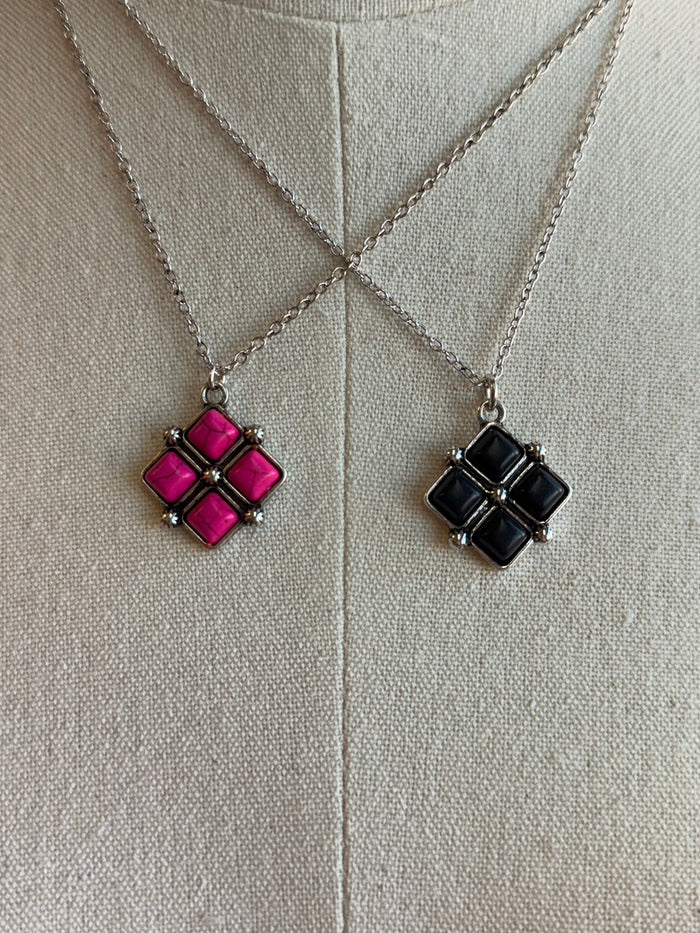 Diamond four-stone pendant set: pink and black square clusters on silver chains