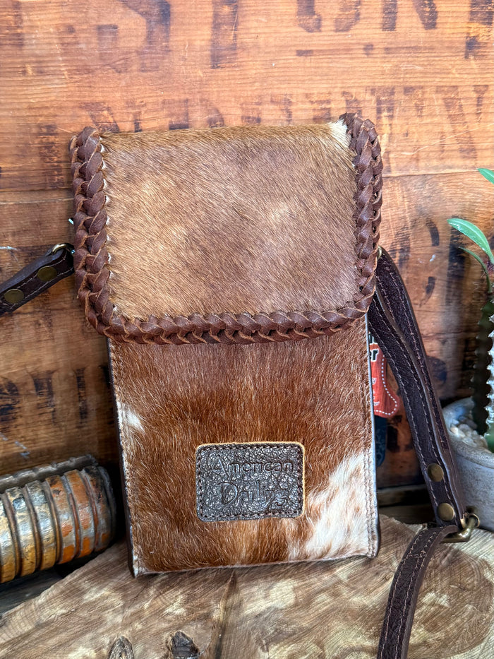 Brown hair-on cowhide crossbody pouch bag with braided edge, flap, and centered logo patch