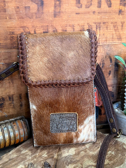 Brown hair-on cowhide crossbody pouch bag with braided edge, flap, and centered logo patch