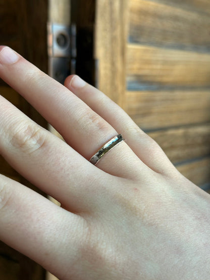 Hammered sterling silver ring close-up on finger, slim band with reflective texture