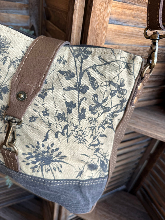 Floral canvas crossbody bag side view with brown leather strap and adjustable ring hardware