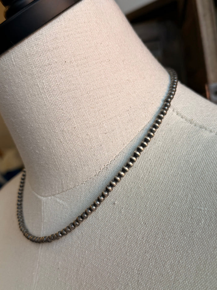 Sterling silver beaded chain necklace detail, rounded beads along the neckline