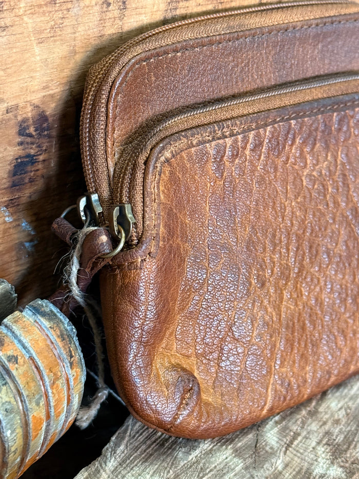 Brown cowhide double-zip coin wallet close-up of side zipper and leather texture